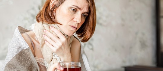 Eine Frau fässt sich vor Schmerzen an den Hals